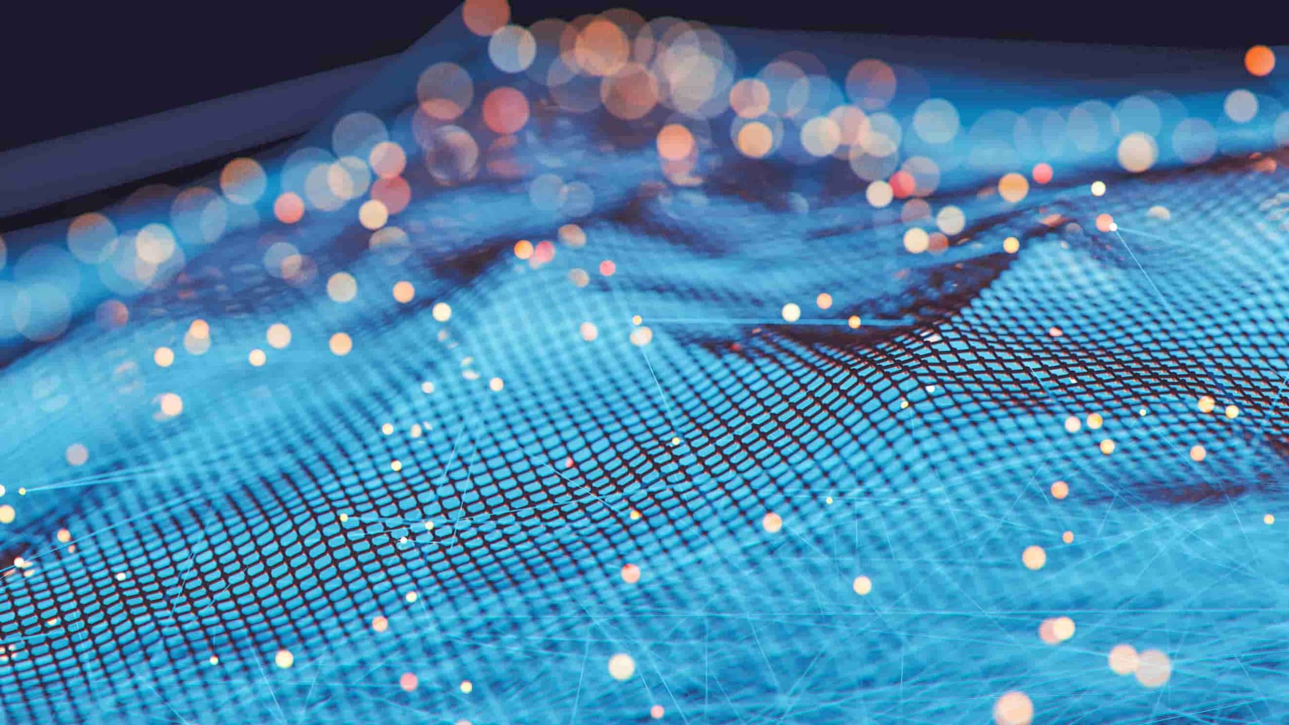 Close-up image of a blue digital network grid with glowing nodes and blurred lights in the background, symbolizing connectivity and advanced technology.