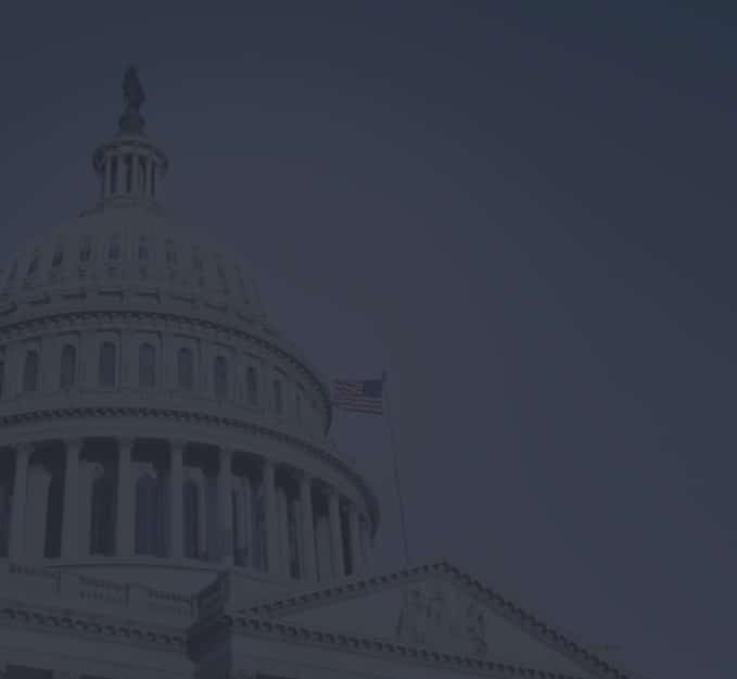 A low-light image of the United States Capitol building with an American flag flying at the top, depicted in silhouette against a dark blue twilight sky, invites viewers to Contact DomainTools for more information.