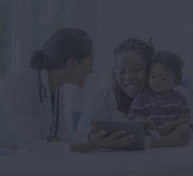 A doctor interacts with a smiling woman and child, using an Internet-enabled tablet in a dimly lit room, evoking a sense of care and attention.