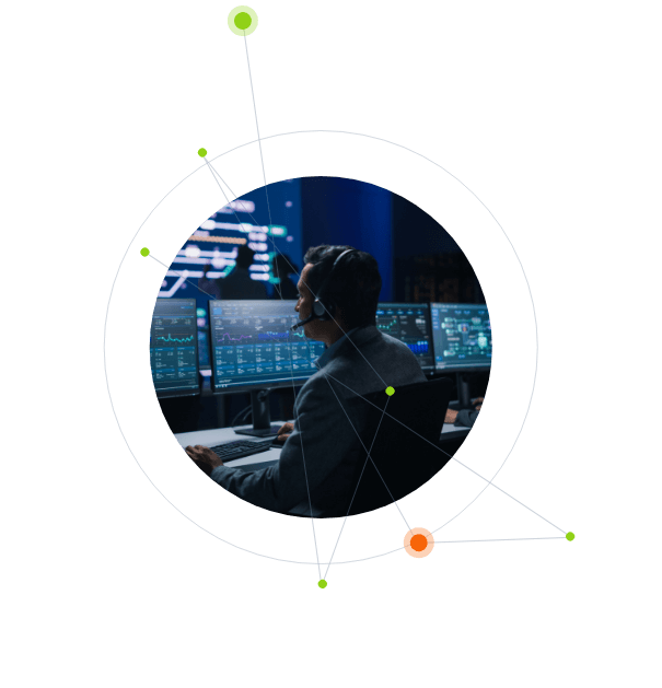 Man in a dark Post-RiskIQ SOC, seated, focused on multiple computer screens displaying data, with a graphic overlay of a scientific atom-like structure.