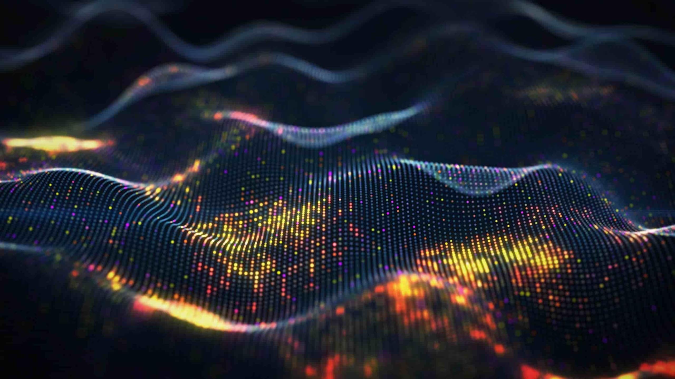 Abstract digital landscape with glowing, multicolored particles forming wave patterns on a dark background, illustrating data or technology concepts.