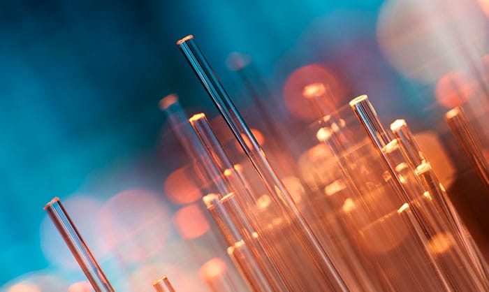 Close-up of laboratory glass pipettes with a blurred background featuring warm bokeh lights, highlighting the clarity and precision of scientific equipment in DomainTools.