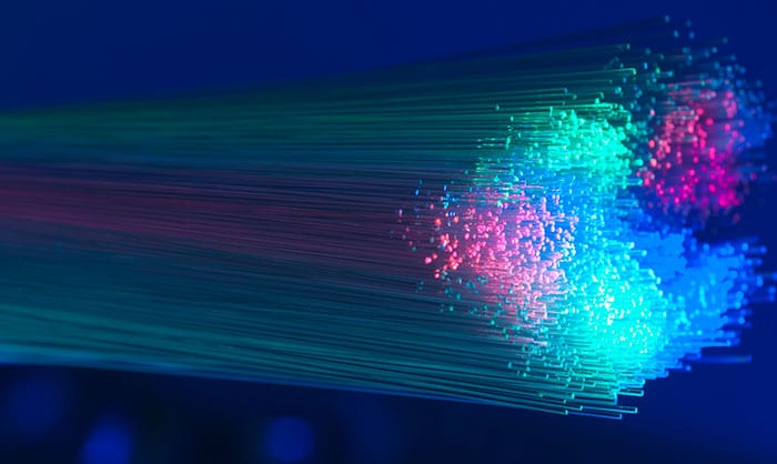 Bundle of fiber optic cables illuminated with vibrant blue, red, and green lights, showcasing the technology's ability to leverage Domain and DNS Intelligence for OEMs.